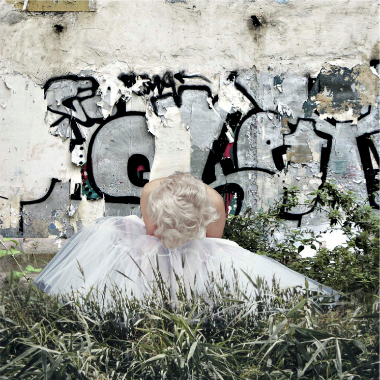 Marilyn Monroe en robe blanche vue de dos devant le même mur de graffitis