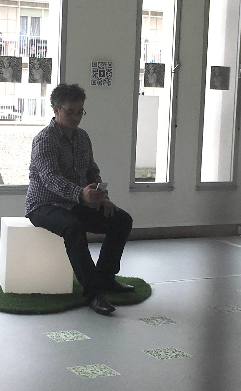 Homme assis sur un pouf blanc dans un espace d'exposition avec projection au sol