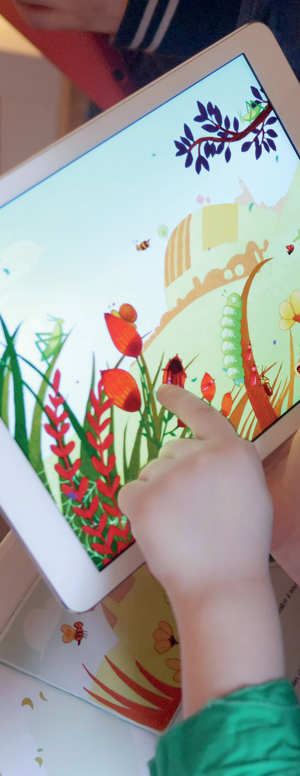 Main d'enfant touchant une tablette avec jardin animé en RA