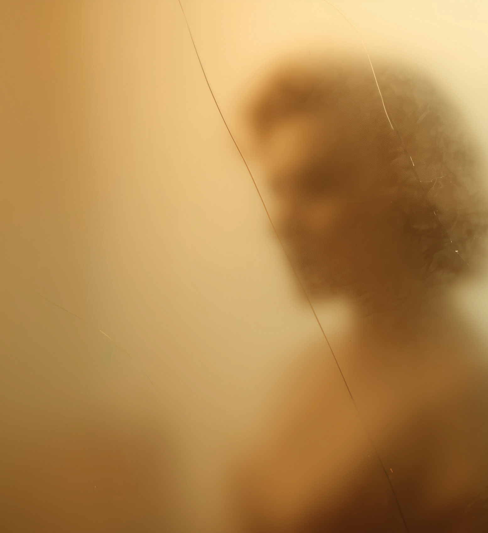 Silhouette floue d'une femme derrière une vitre embuée, sépia